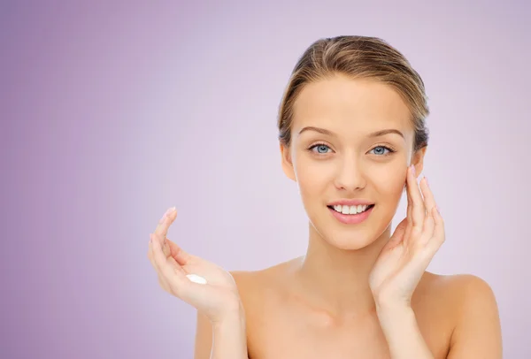 Feliz joven mujer aplicando crema a su cara — Foto de Stock