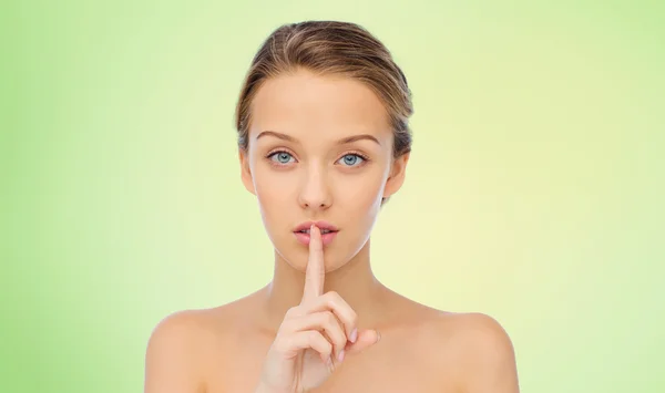 Beautiful young woman holding finger on lips — Stock Photo, Image