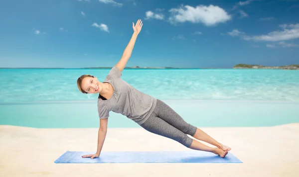 Kvinna att göra yoga i side plank pose på stranden — Stockfoto