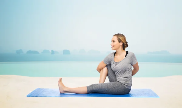 Mulher fazendo ioga em twist pose no tapete — Fotografia de Stock