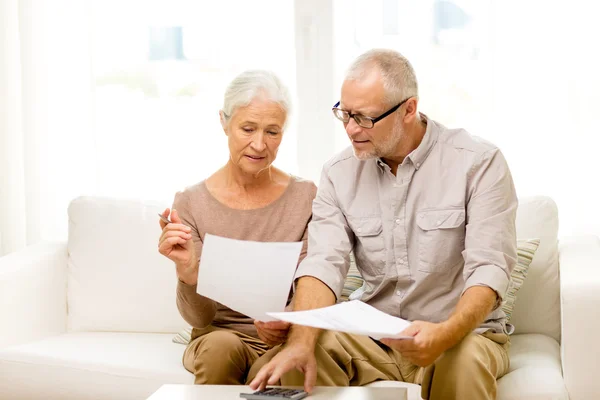 Couple aîné avec papiers et calculatrice à la maison — Photo