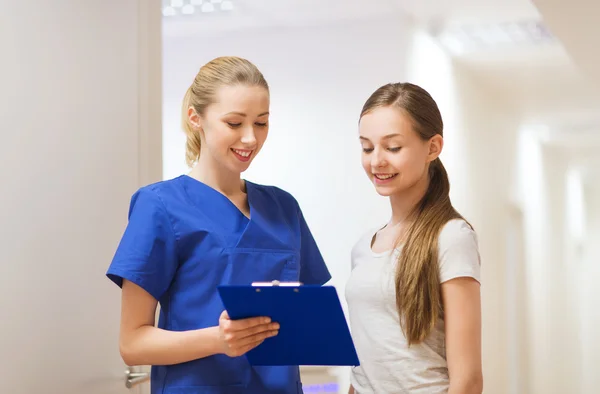 Doctor or nurse with clipboard and girl patient — Stock Photo, Image