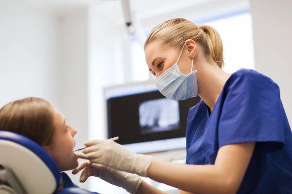 Dentista femenino chequeando dientes de niña paciente — Foto de Stock