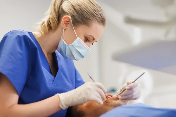 Dentiste femelle vérifiant les dents du patient masculin — Photo