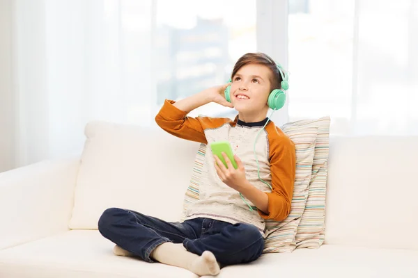 Menino feliz com smartphone e fones de ouvido em casa — Fotografia de Stock