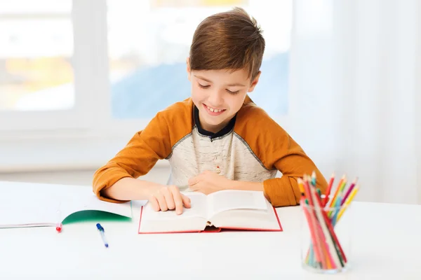 Lächelnder, studierender Junge, der zu Hause Buch liest — Stockfoto