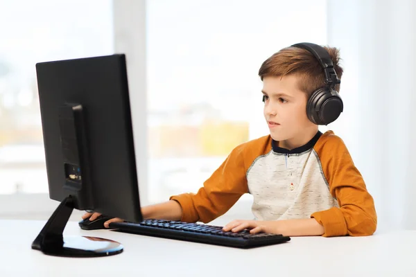 Happy boy with computer and headphones at home — Stock Photo, Image