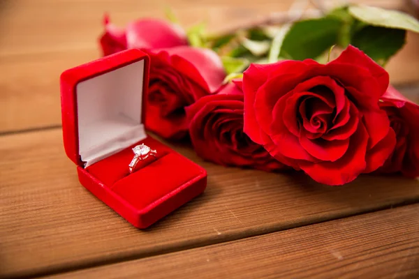 Nahaufnahme von Diamant-Verlobungsring und roten Rosen — Stockfoto