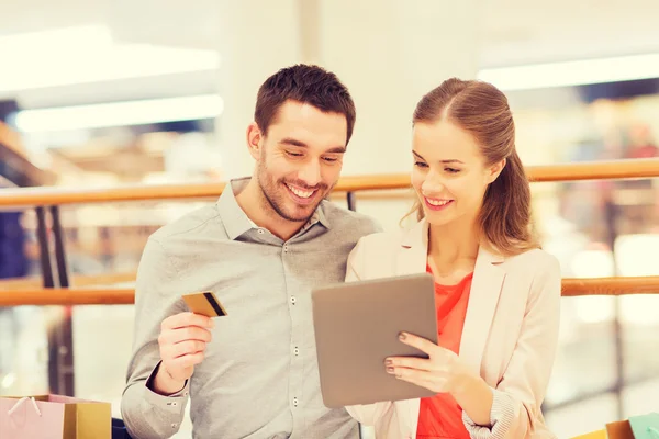 Casal com tablet pc e sacos de compras no shopping — Fotografia de Stock