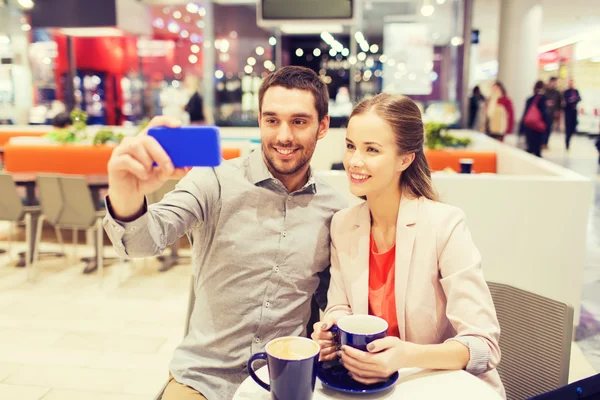 Happy couple with smartphone taking selfie in mall — Stock Photo, Image