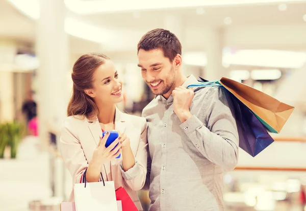 Coppia con smartphone e shopping bag nel centro commerciale — Foto Stock