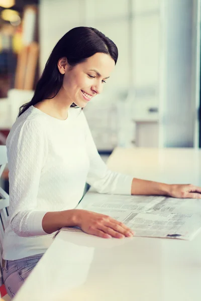 Lächelnde junge Frau liest Zeitung im Café — Stockfoto