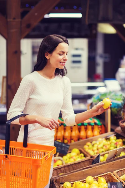 Feliz joven con cesta de comida en el mercado — Foto de Stock