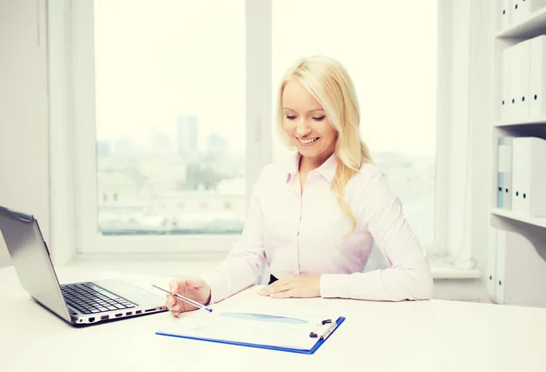 Sorridente donna d'affari che legge i giornali in ufficio — Foto Stock