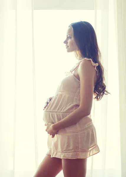 Happy pregnant woman near window at home — Stock Photo, Image