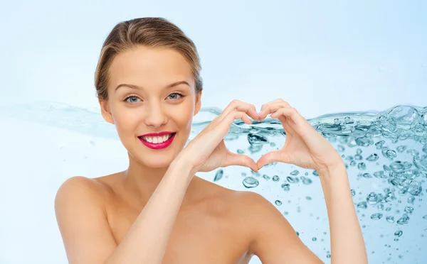 Sonriente joven mujer mostrando corazón forma mano signo — Foto de Stock