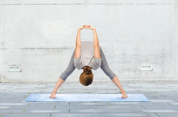 Vrouw maken yoga wide-legged forward bend op mat — Stockfoto