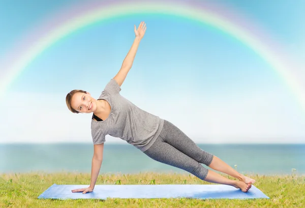Vrouw maken yoga in zijkant plank pose op de mat — Stockfoto