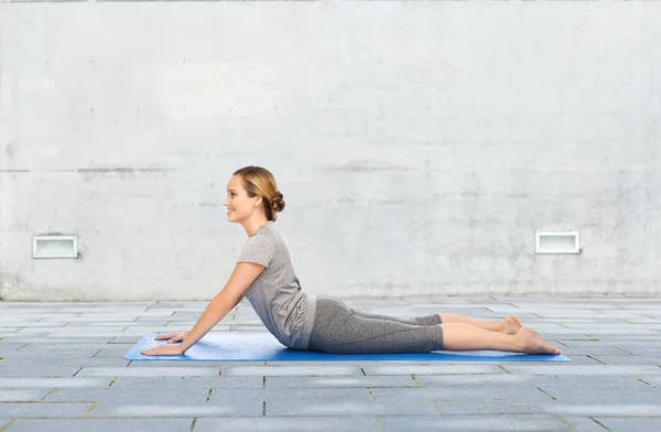 Женщина делает yoga в позе собаки на циновке — стоковое фото