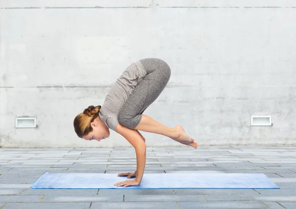 Donna che fa yoga in posa gru sul tappeto — Foto Stock