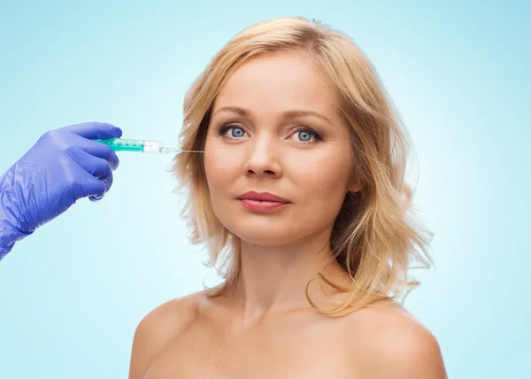 Woman face and beautician hand with syringe — Stok fotoğraf