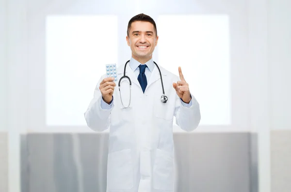 Улыбающийся врач в белом халате с таблетками — стоковое фото