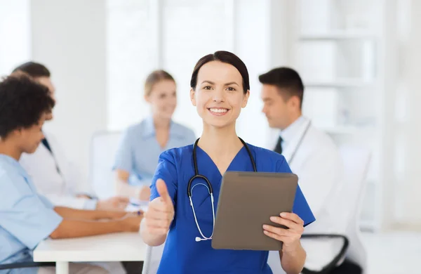 Médico feliz com tablet pc sobre a equipe na clínica — Fotografia de Stock