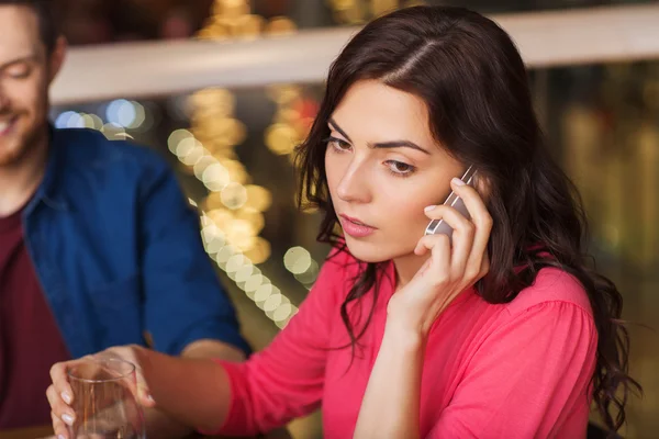 Woman with smartphone and friends at restaurant — Stock Photo, Image