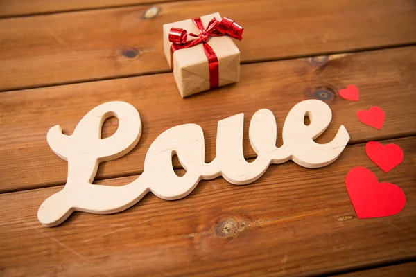 Primer plano de la palabra amor con caja de regalo y corazones rojos —  Fotos de Stock