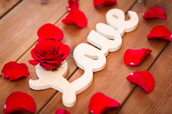 Крупним планом слово кохання вирізати з червоною трояндою на дереві Ліцензійні Стокові Фото