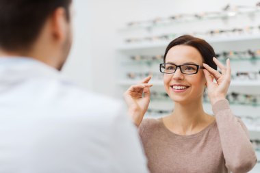 woman choosing glasses at optics store clipart