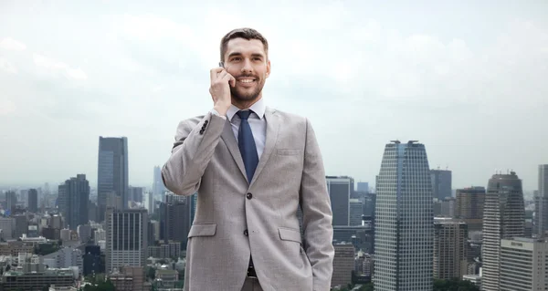 Lachende zakenman met smartphone in stad — Stockfoto