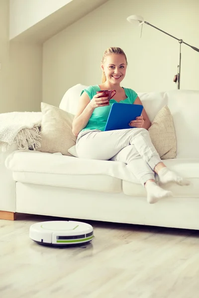 Счастливая женщина с планшетным компьютером, пьющая чай дома — стоковое фото