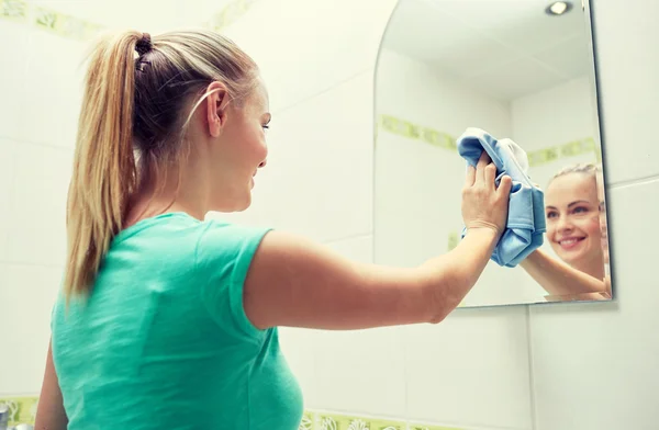 Mujer feliz espejo de limpieza con trapo — Foto de Stock