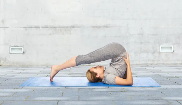 Vrouw maken van yoga in ploeg pose op de mat buitenshuis — Stockfoto