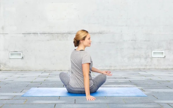 Vrouw maken van yoga in twist pose op de mat buitenshuis — Stockfoto