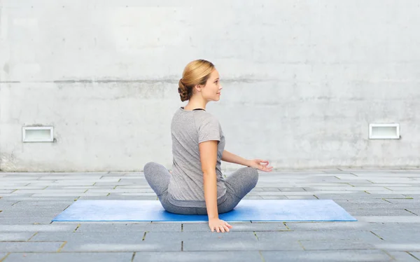 Mujer haciendo yoga en actitud de giro en la estera al aire libre —  Fotos de Stock