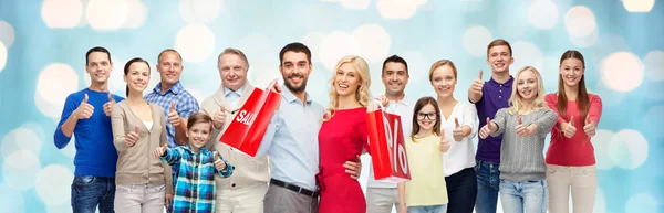 Gente feliz con bolsas de compras mostrando los pulgares hacia arriba — Foto de Stock