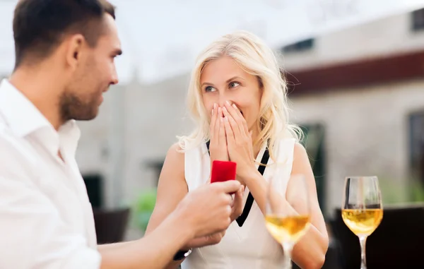 Gelukkige paar met verlovingsring en wijn in café — Stockfoto