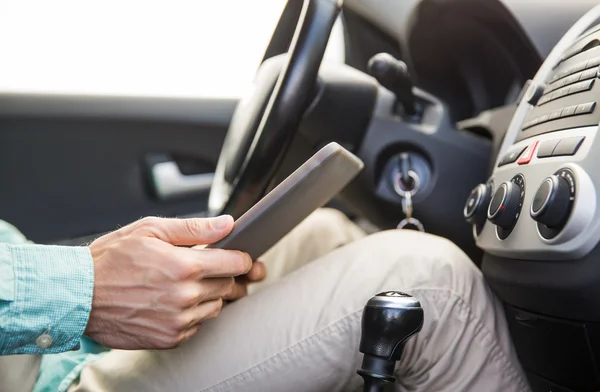 Primer plano de hombre joven con tablet PC coche de conducción —  Fotos de Stock