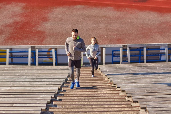 Happy couple running upstairs on stadium — Stock Photo, Image