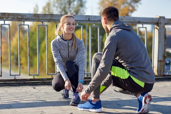 Coppia sorridente allacciatura lacci delle scarpe all'aperto — Foto Stock