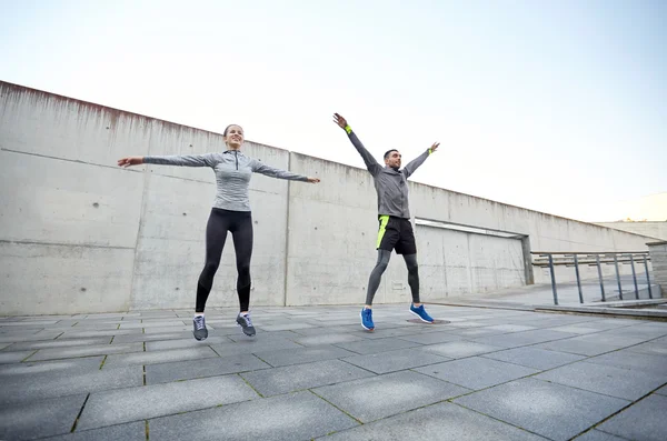 Happy man and woman jumping outdoors — Stock Photo, Image