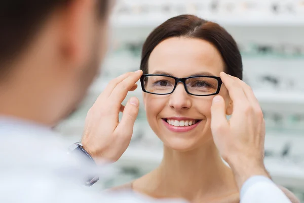 Optician putting glasses to woman at optics store — Stock Photo, Image