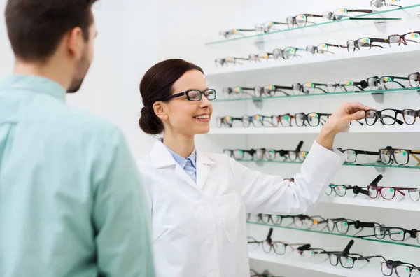 Optician showing glasses to man at optics store — Stock Photo, Image