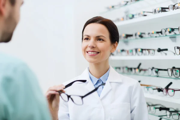 Optician showing glasses to man at optics store — Stock Photo, Image