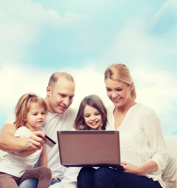 Familia feliz con ordenador portátil y tarjeta de crédito —  Fotos de Stock