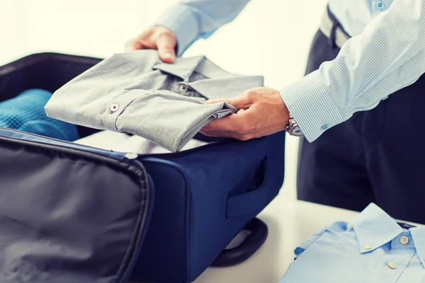 Uomo d'affari imballaggio vestiti in borsa da viaggio — Foto Stock