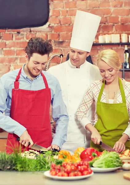 Happy couple and male chef cook cooking in kitchen — Stock Photo, Image