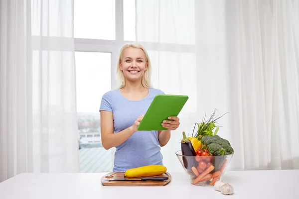 Sorrindo jovem com tablet pc cozinhar em casa — Fotografia de Stock